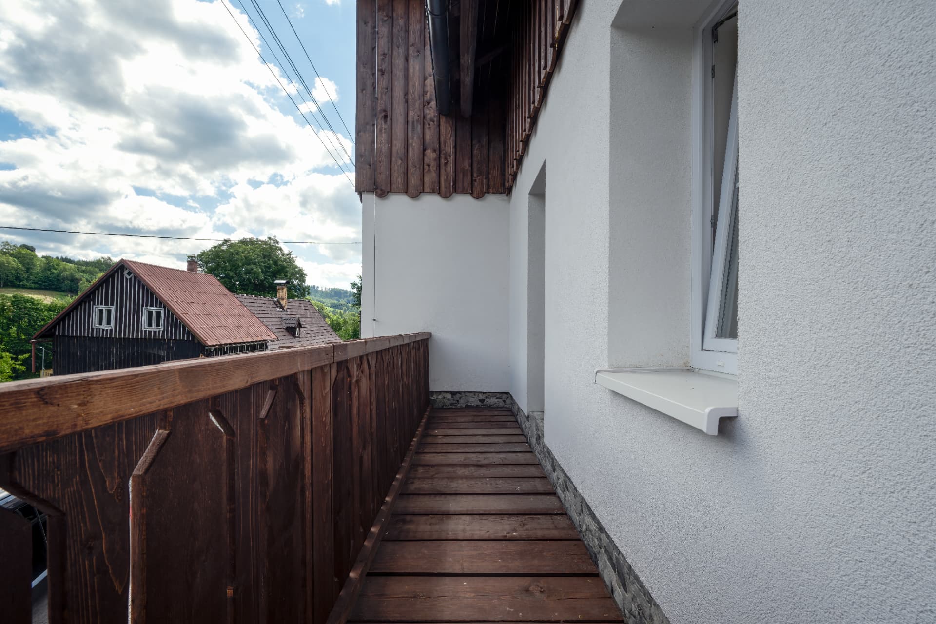 Dřevěný balkon s výhledem do údolí a na okolní roubené domy